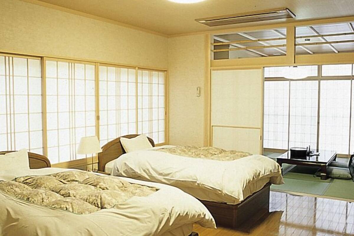 Une chambre d’hôtel avec deux lits, un bureau et une vue sur l’extérieur grâce à de grandes fenêtres.