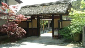 A traditional Japanese building with a thatched roof and wooden pillars. - Oyado Sansui (Achi)