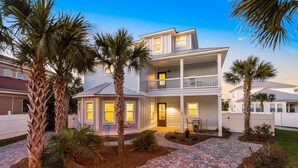 A two-story house with a balcony, surrounded by palm trees and a paved driveway. - SEA YOU SOON: Gorgeous Home in Gated Neighborhood w/ Private Pool & Easy Beach Access! (Miramar Beach)