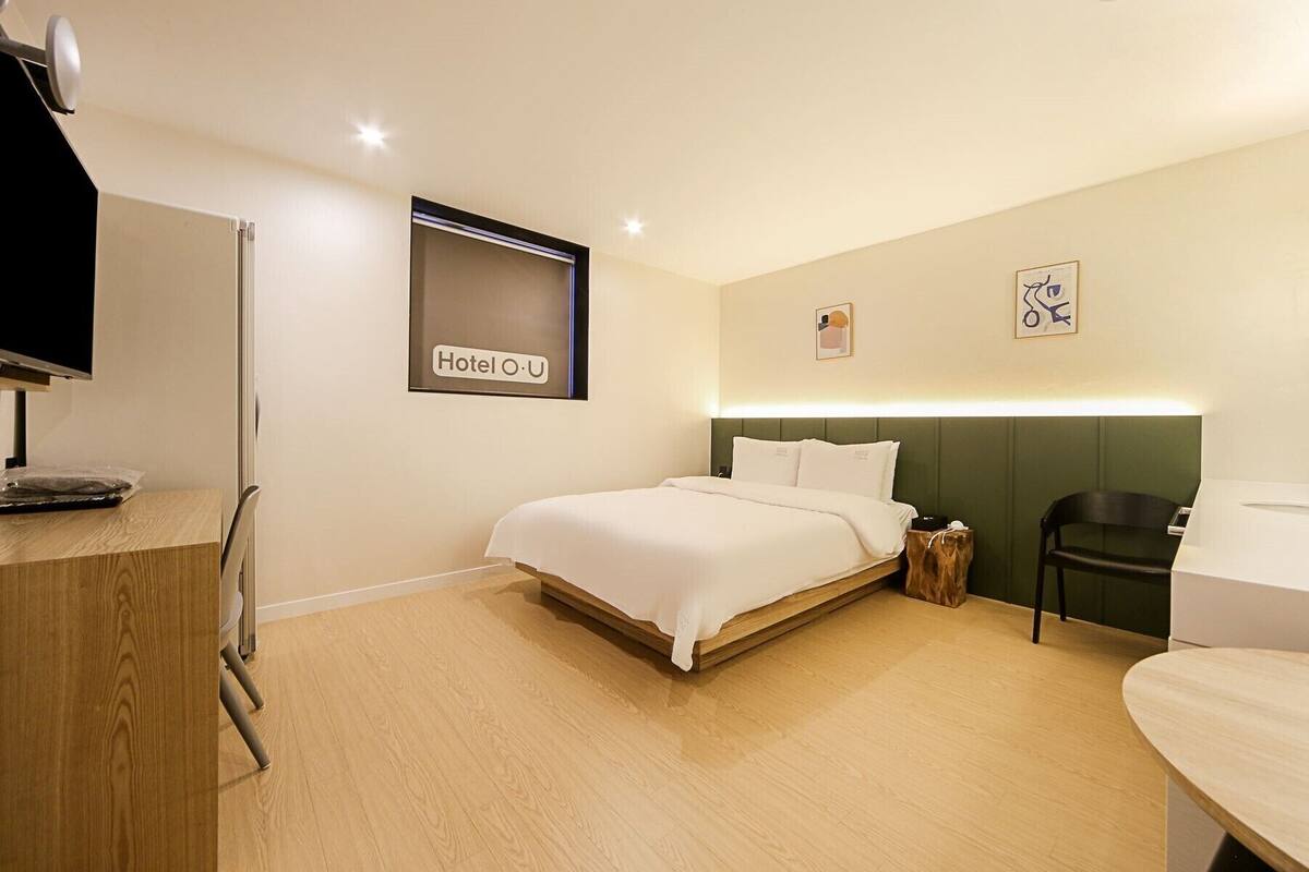Ein Hotelzimmer mit einem Bett, einem Schreibtisch mit Computer, einem Sessel und einem kleinen Tisch.