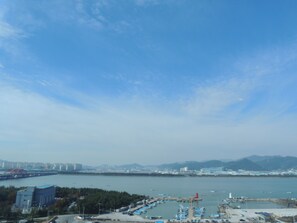 A marina with boats, a lighthouse, and a bridge in the background.