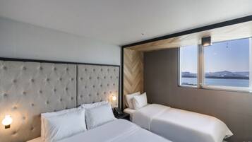 A hotel room with a large bed, two bedside tables, a headboard, and a window with a view of the city.