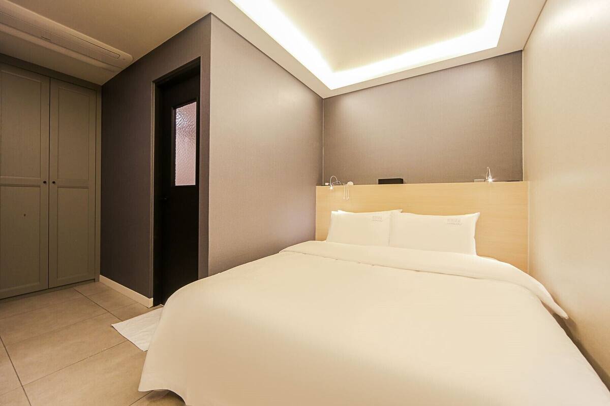 Ein Hotelzimmer mit Bett, Kleiderschrank und Dachfenster.