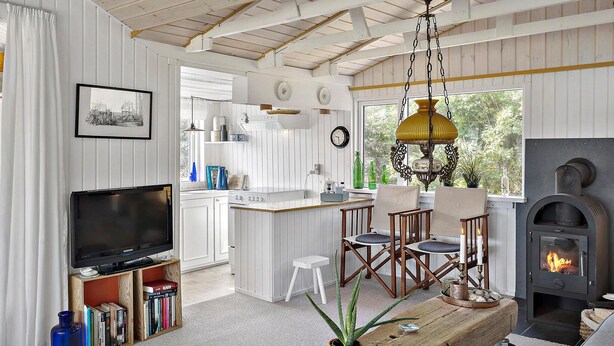 A cozy living room with a TV, bookshelves, a dining area, and a fireplace.