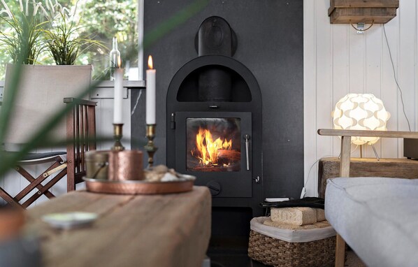 A cozy room with a wood-burning stove, a table with candles, and a lamp. - 2 bedroom amazing home in Ulfborg (Ulfborg)