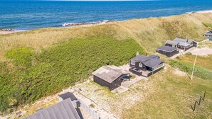 A coastal property with a large grassy area, several buildings, and a view of the sea.