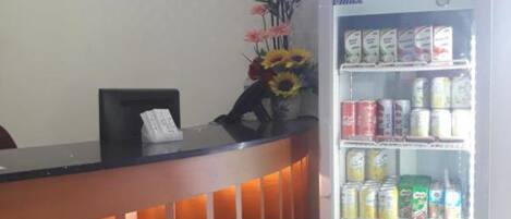 A reception desk with a refrigerator stocked with beverages and a vase of flowers.