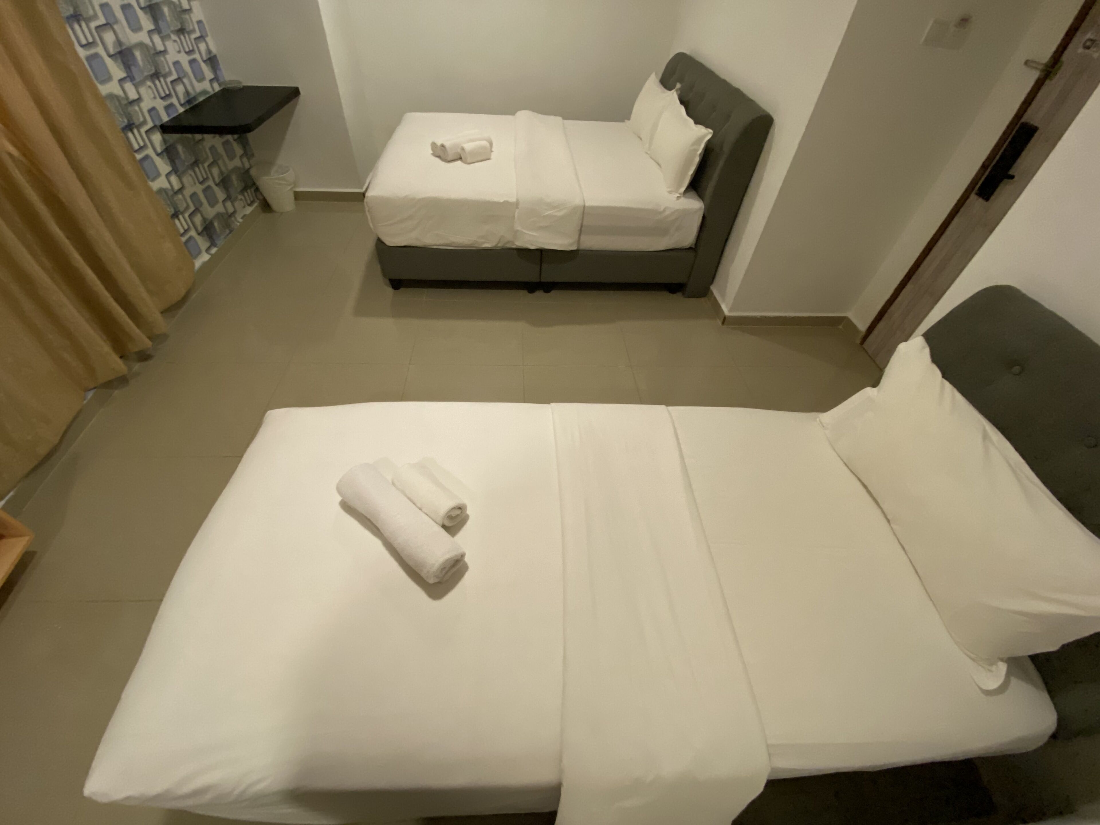 Ein Hotelzimmer mit einem großen Bett, einem kleineren Bett und einem Badezimmer.