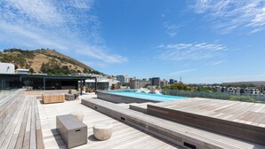 A rooftop terrace with a swimming pool, wooden deck, and seating areas. - The Docklands 509 by CTHA (Cape Town)