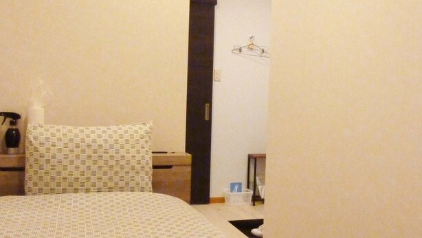 Una habitación de hotel con cama, mesita de noche, cómoda, espejo y perchero.