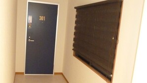 Un pasillo con una puerta con la etiqueta '301' y una ventana con persianas.