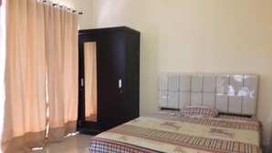 Une chambre à coucher avec un lit, une armoire et un rideau.