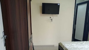 Une chambre à coucher avec un lit, un téléviseur fixé au mur et une armoire.