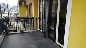 Un balcon avec une balustrade en métal, une porte noire et un mur jaune.