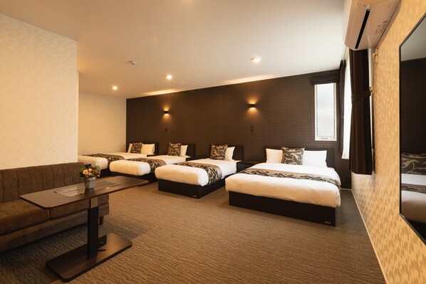 A hotel room with three beds, a sofa, a small table, and a large window. - GRAND BASE Nagasaki Ekimae (Nagasaki)