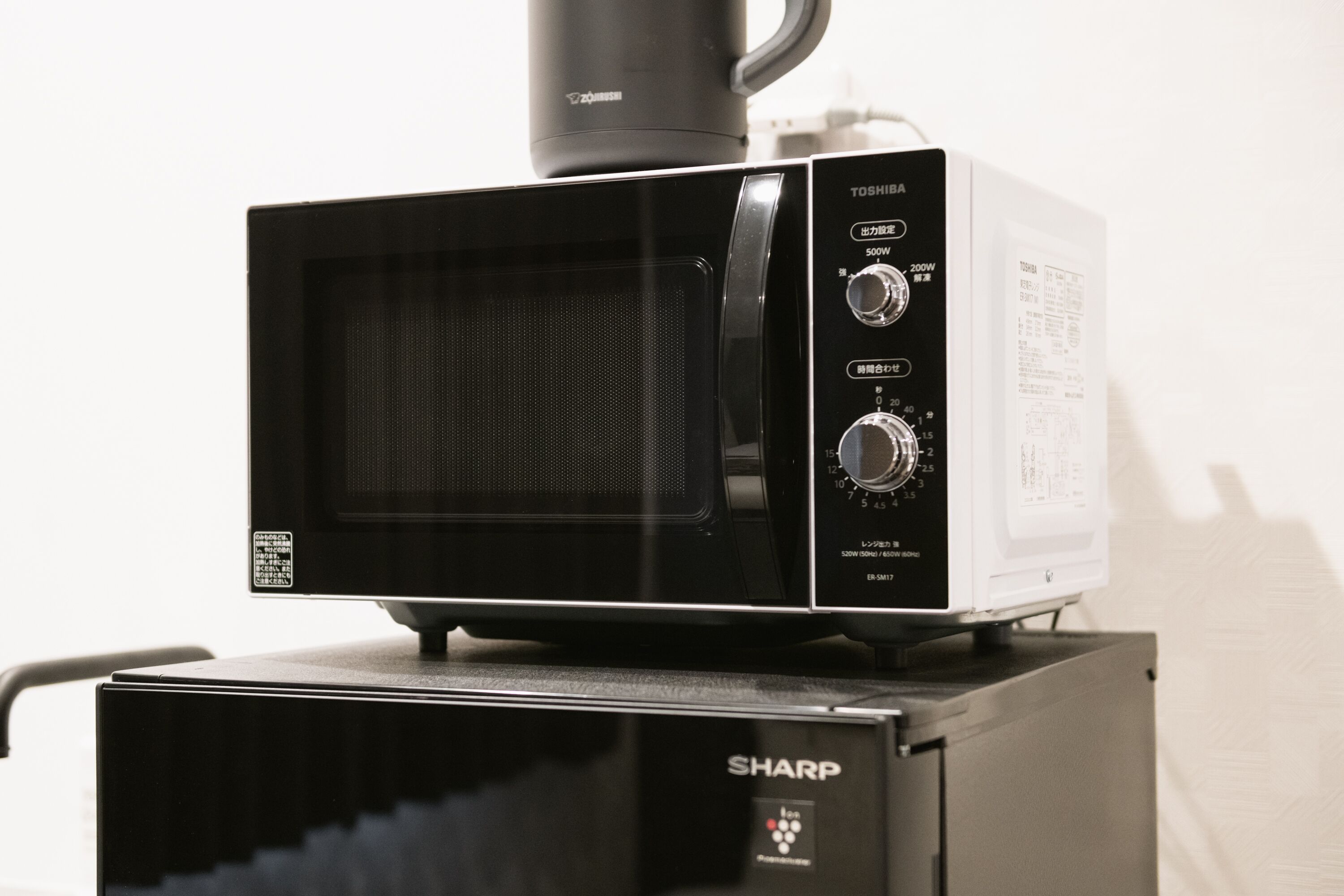 A microwave oven with a digital display and control panel, placed on a black Sharp appliance.