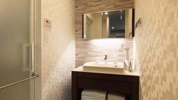 Un baño con pared de azulejos, un lavamanos con espejo y un toallero con toallas dobladas.