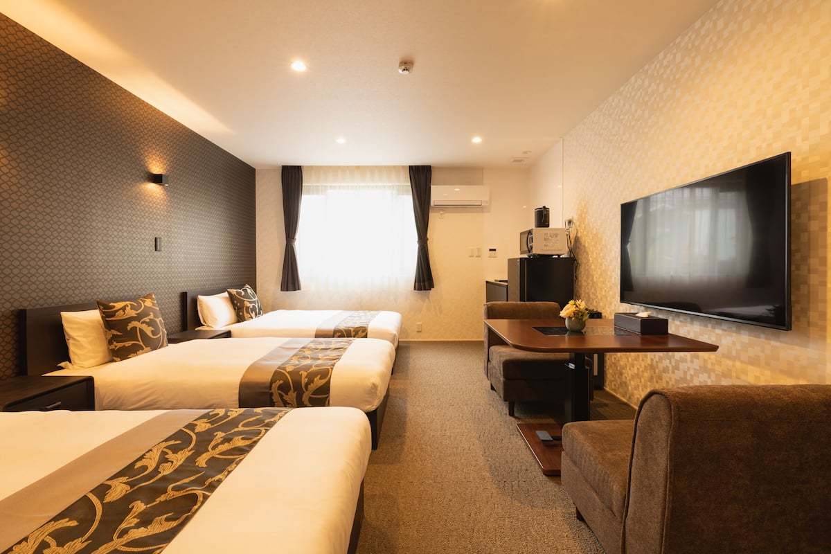 Une chambre d’hôtel avec deux lits, une télévision, un bureau et un canapé.
