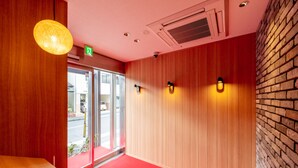 A hotel lobby with wooden paneling, a red carpet, and a brick wall. - Grand Base Hiroshima Hikarimachi (Hiroshima)