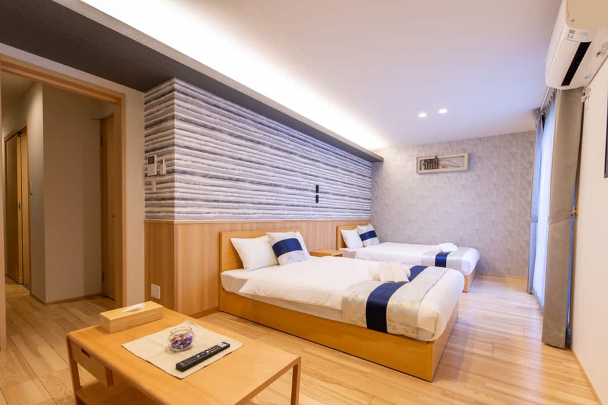 A hotel room with two beds, a wooden table, and a small seating area.