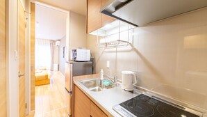 A modern kitchen with wooden cabinets, a stainless steel sink, and a built-in stove. - Grand Base Hiroshima Hikarimachi (Hiroshima)