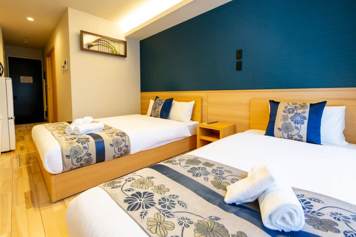 A hotel room with two beds, a wooden headboard, and a nightstand.
