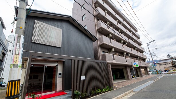 A multi-story building with a red carpet entrance, a parking sign, and a visible entrance door. - Grand Base Hiroshima Hikarimachi (Hiroshima)