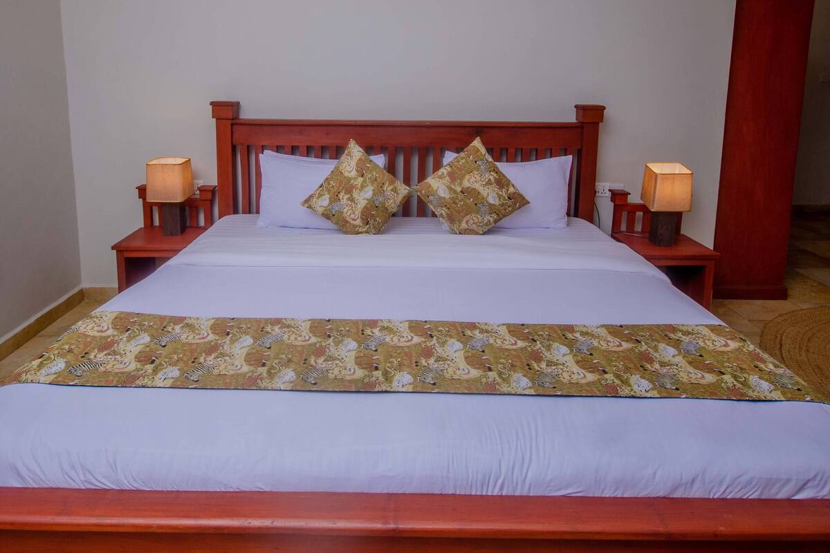 A bed with a wooden headboard, two bedside lamps, and a patterned bedspread.