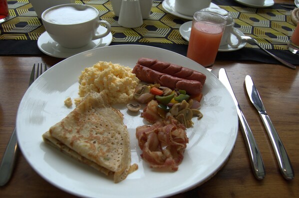 A breakfast plate with eggs, sausage, mushrooms, and bacon. - Amani Safari Lodge (Arusha)