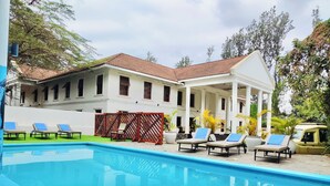 Uma área de piscina com espreguiçadeiras e um edifício com telhado em azulejos.