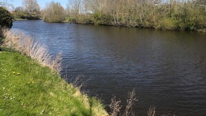 Un río tranquilo bordeado de árboles y hierba.