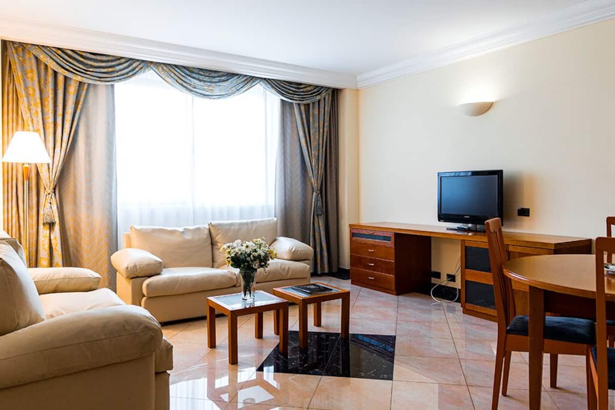 Uma sala de estar moderna com sofá, mesa de centro, TV e área de refeições.