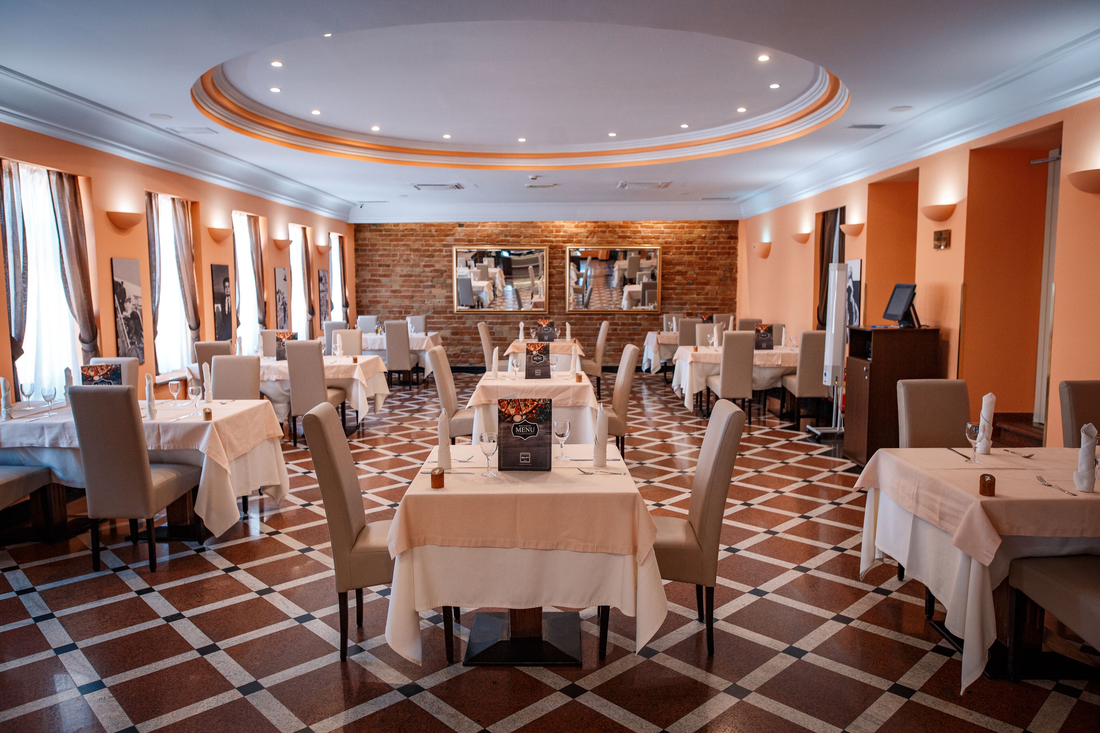 Un restaurante con varias mesas y sillas, una pared de ladrillo y un suelo con diseño de cuadros.