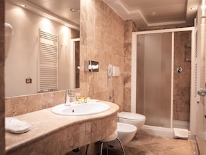 Un baño moderno con encimera de mármol, inodoro, ducha y espejo.