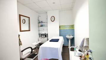 Guests can relax on the treatment table or sit in the chair, with a sink and mirror nearby.