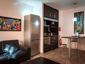 A compact living space with a kitchenette, a dining area, and a sofa. - River Palace Hotel (Atyrau)