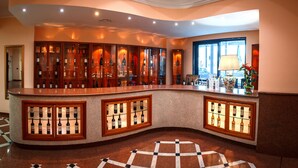 A bar area with a curved counter, wine bottles, and a checkered floor pattern.