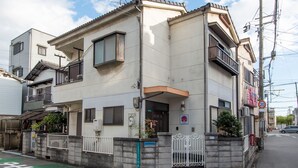 Un edificio residencial de dos pisos con balcón, entrada con reja y señal de tráfico que indica un límite de velocidad de 20 km/h.