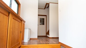 Un pasillo estrecho con suelo de madera, un cubo de basura blanco y un armario de madera.