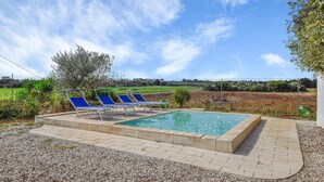 Ein Poolbereich mit vier blauen Liegestühlen und einem rechteckigen Pool.