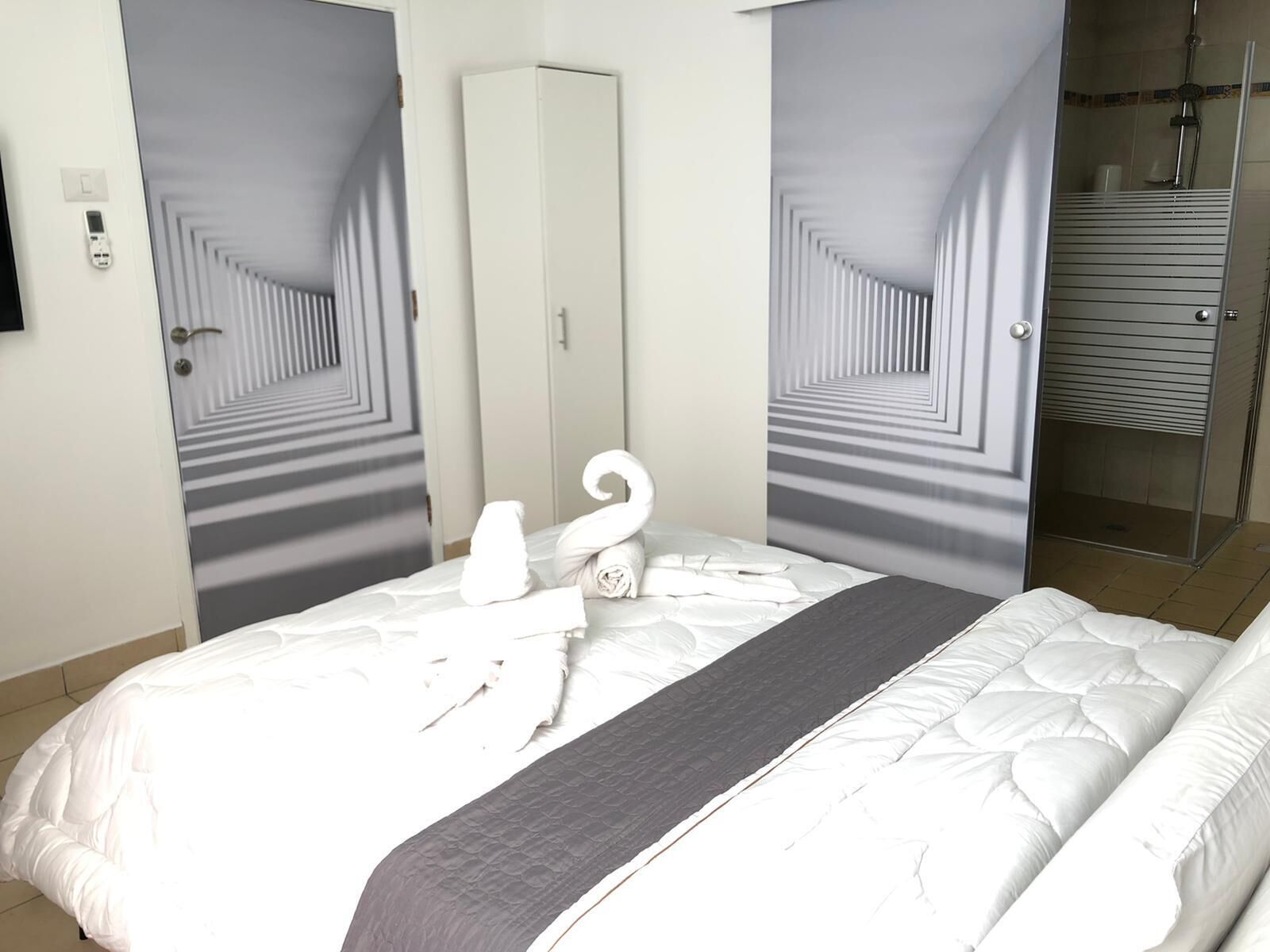 Een hotelkamer met een bed, een spiegel en een douche.