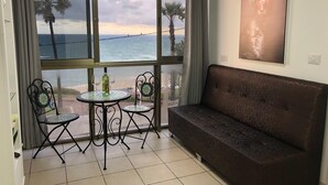 Een balkon met uitzicht op zee, een bank en twee stoelen met een tafel.