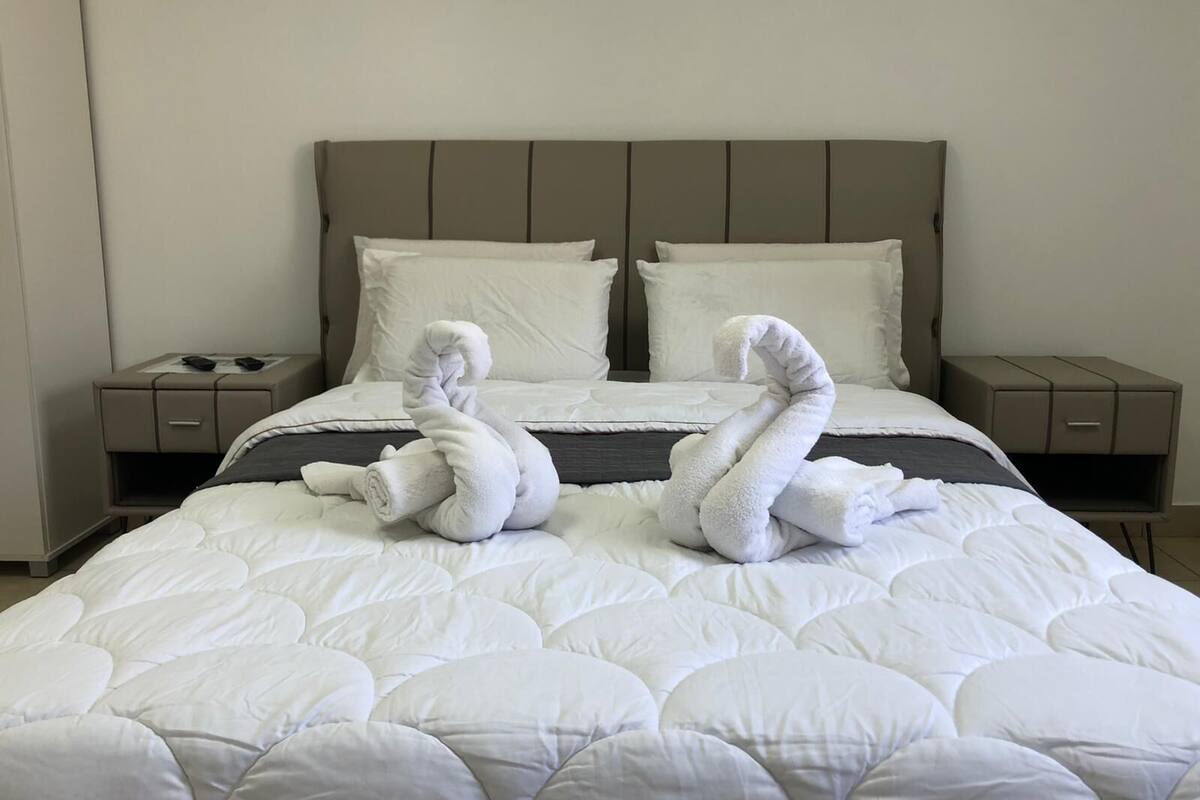 Quarto de hotel com uma cama, duas mesas de cabeceira e uma cabeceira.