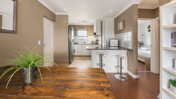 Una cocina moderna con una isla central, taburetes de bar y una planta en maceta.