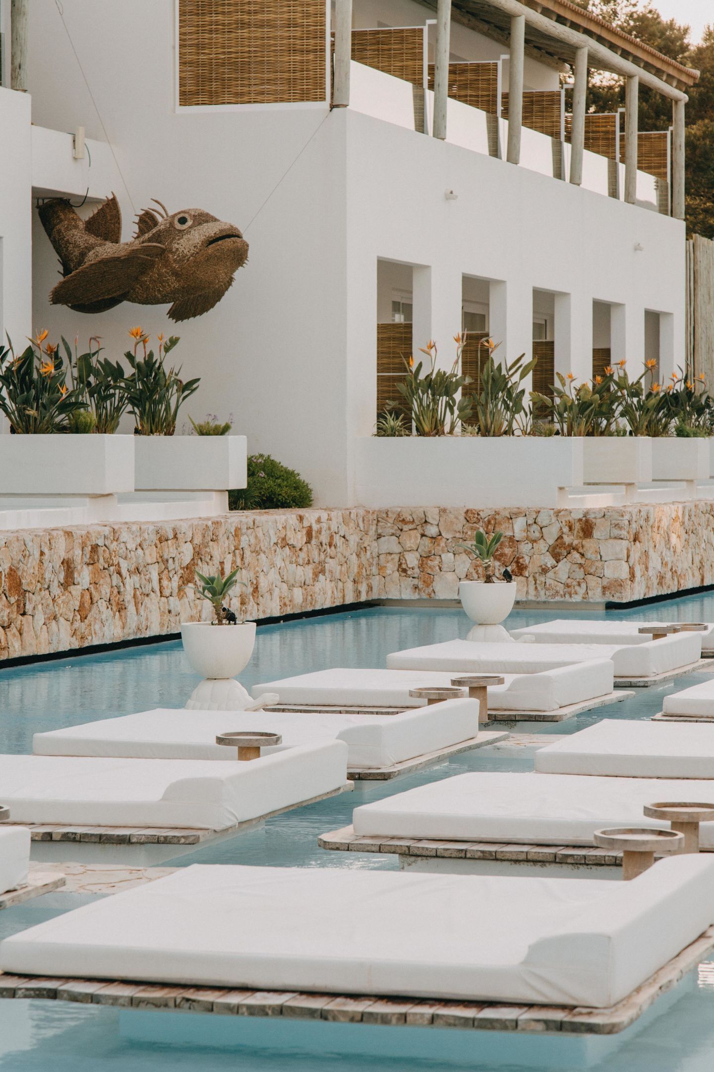 A poolside area with lounge chairs and a large fish sculpture on the wall.