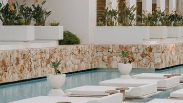 A poolside area with lounge chairs and a large fish sculpture on the wall.