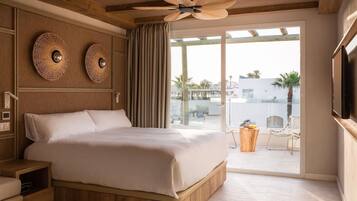 Une chambre spacieuse avec un grand lit, une tête de lit en bois et un ventilateur de plafond.
