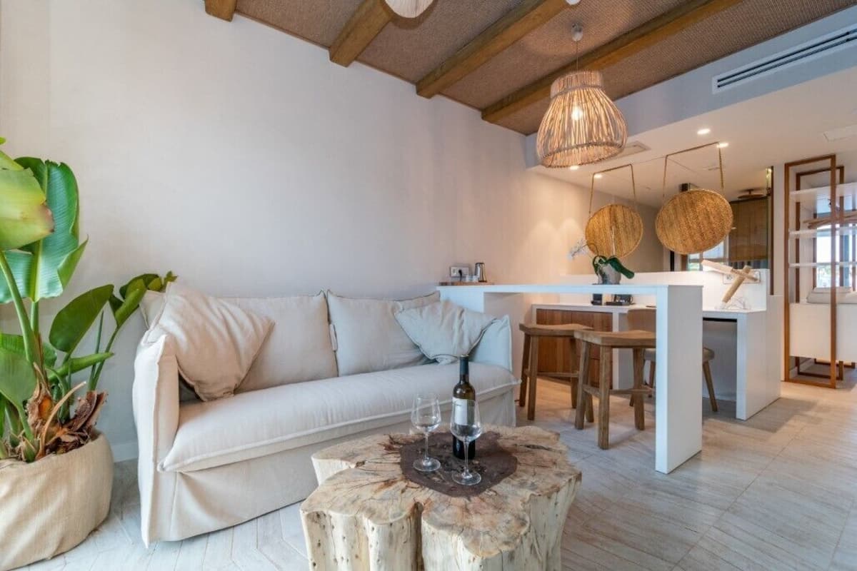 A modern living room with a sofa, a wooden coffee table, and a dining area with a white table and chairs.