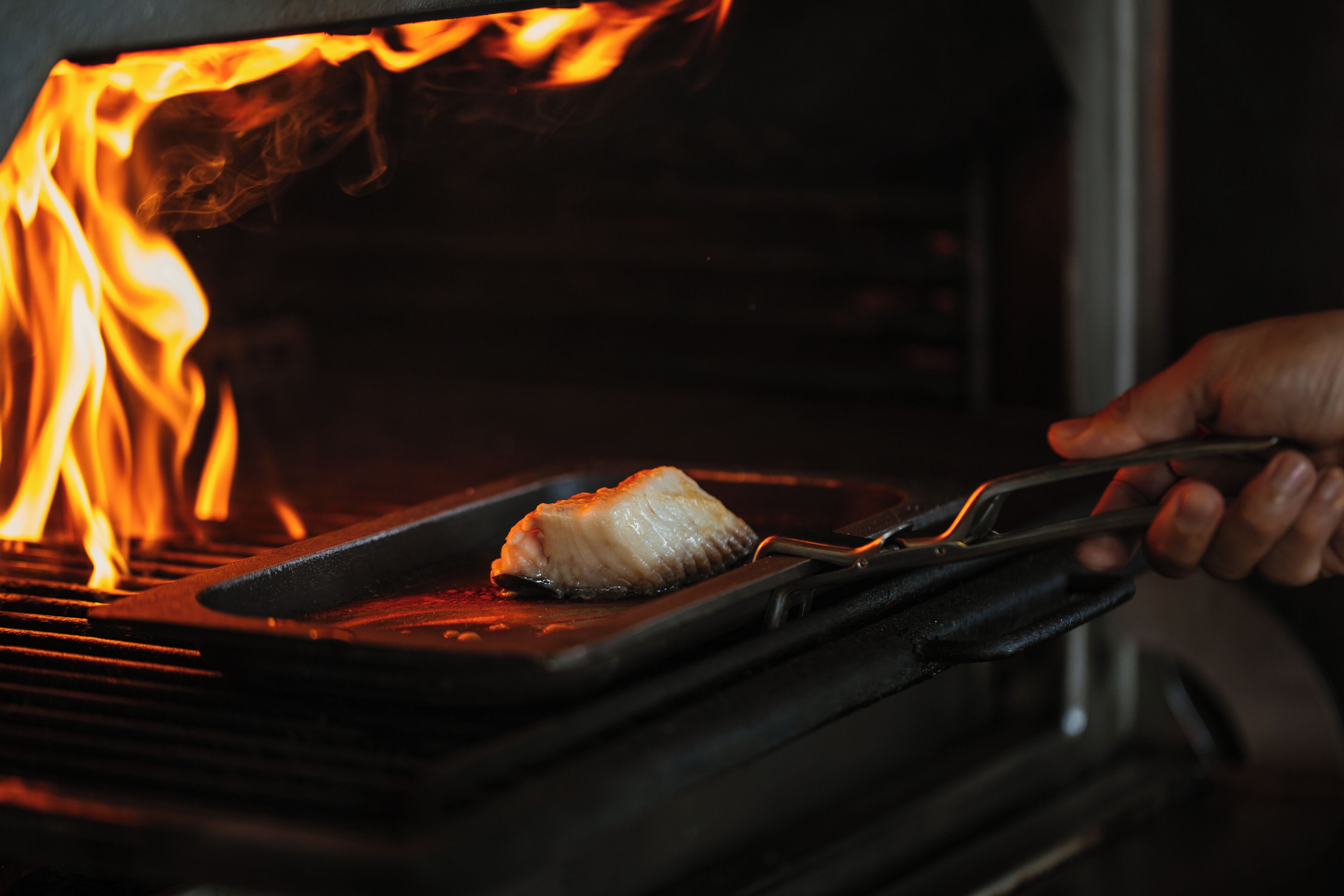 A fish being grilled in a grill pan inside an oven.