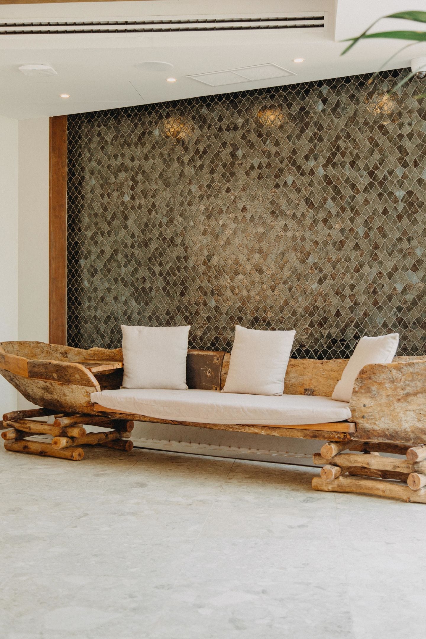 Ein Holzsofa mit Kissen vor einer strukturierten Wand.
